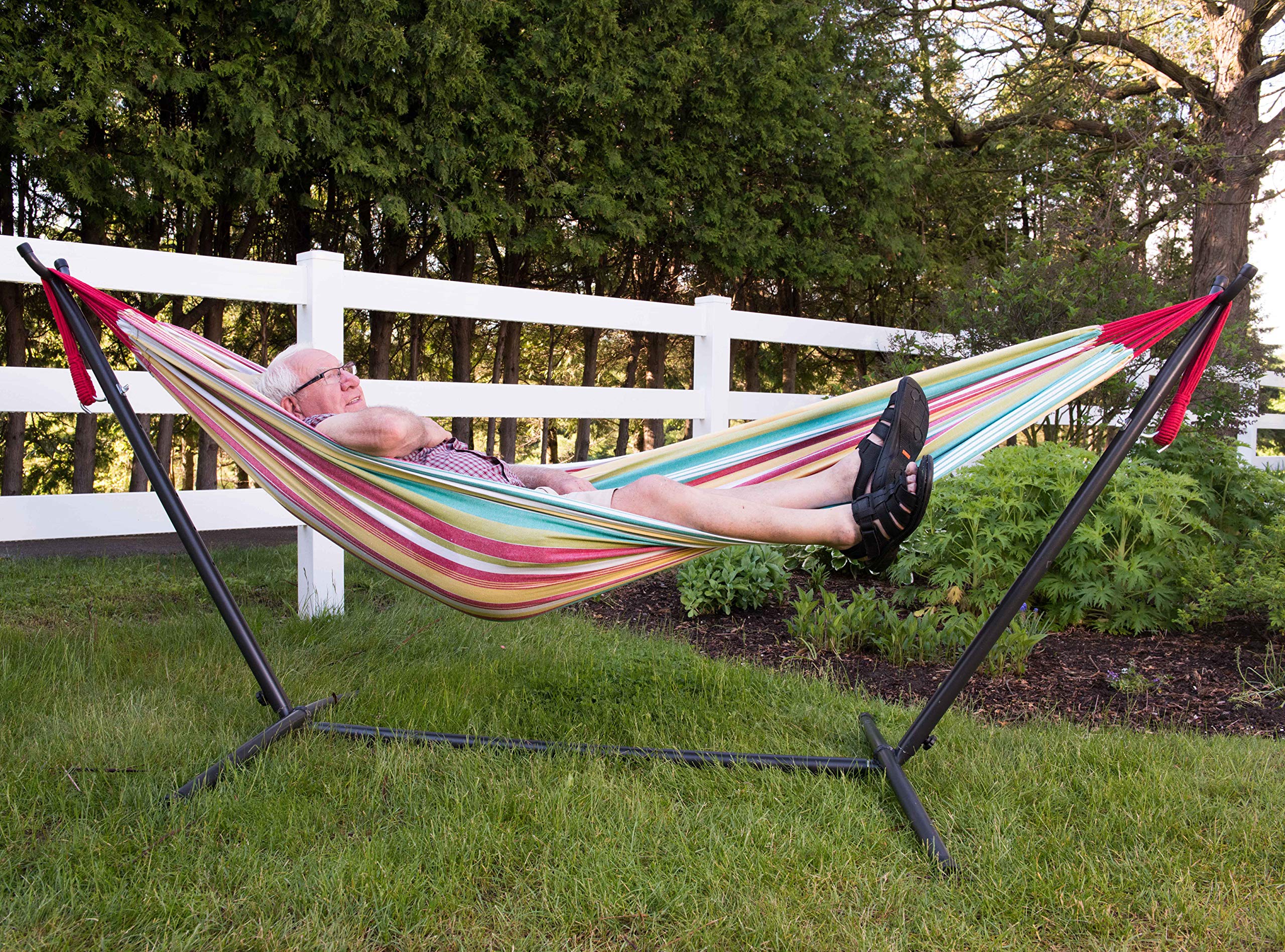Abuelito descansando en hamaca Vivere a rayas de colores con estructura en jardín