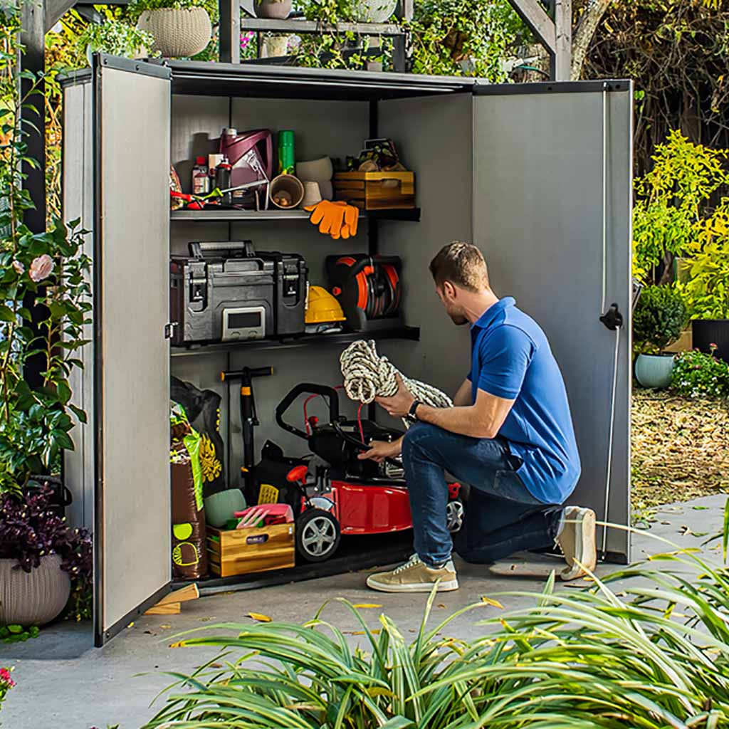 Hombre ordenando enseres de jardinería en armario exterior keter High Store