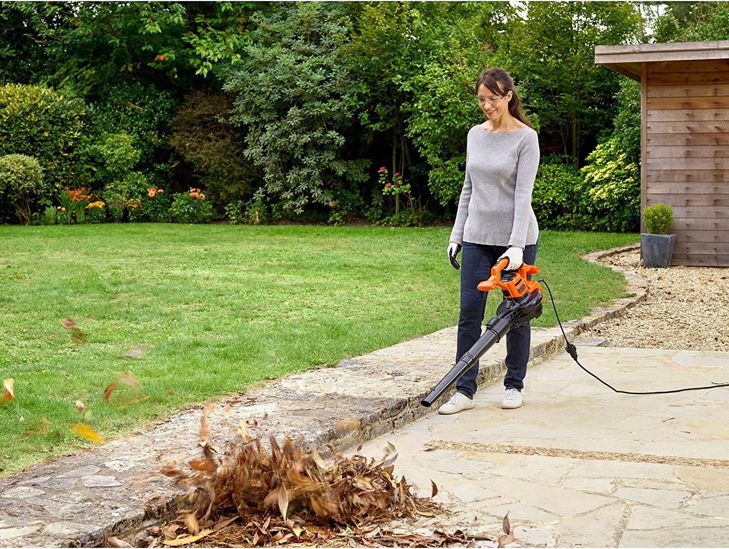 Vista en jardín soplando con el Aspirador soplador triturador de hojas, 2500W, 310 Km/h. BLACK+DECKER GW2500-QS