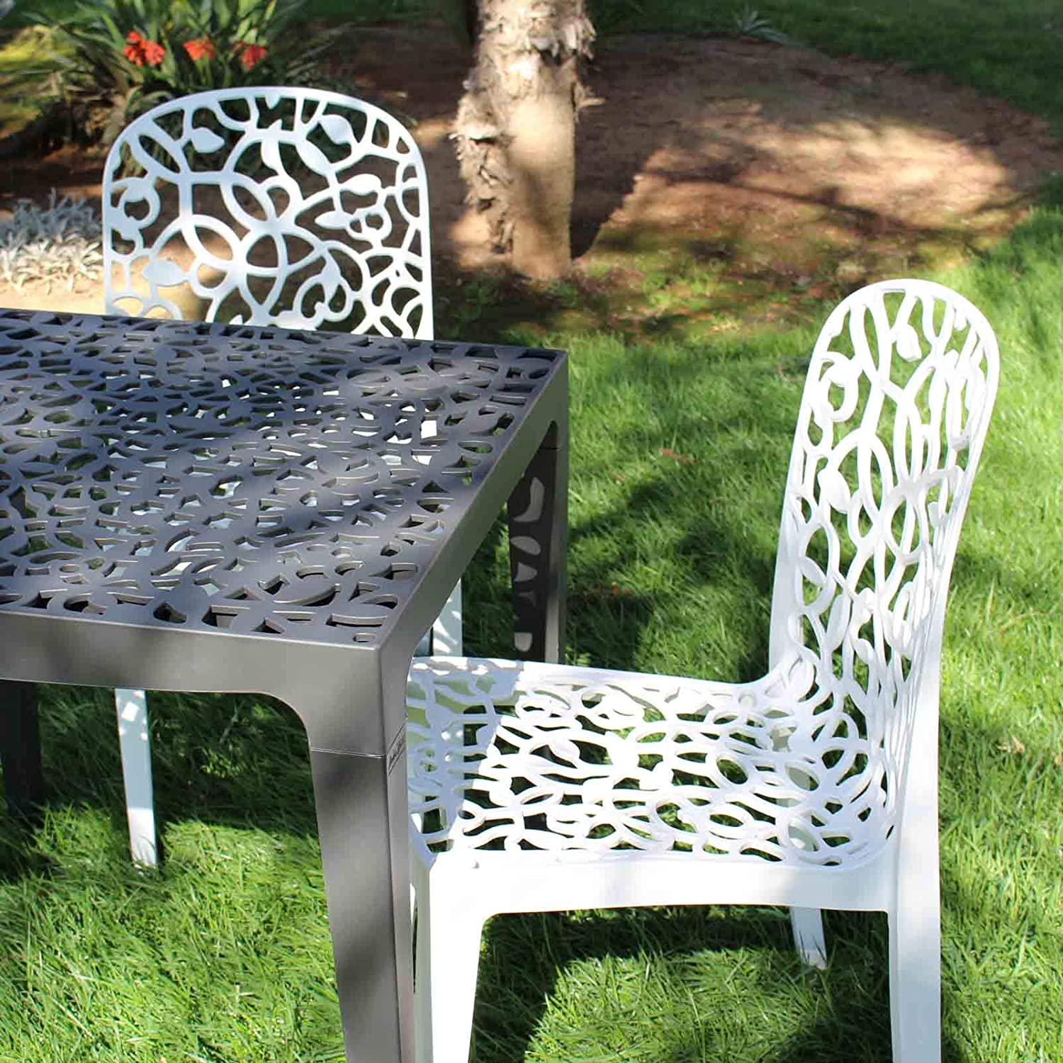 Vista en jardín con el juego de 6 Sillas apilables de interior exterior Flora. 87x50x47 cm, blanco, hecho en España. Shaf