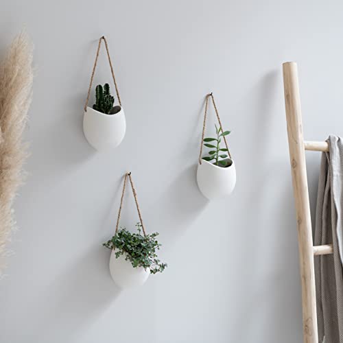 Bonito pack de 3 macetas Kazai colgadas de color blanco con plantitas sobre pared blanca en ambiente interior