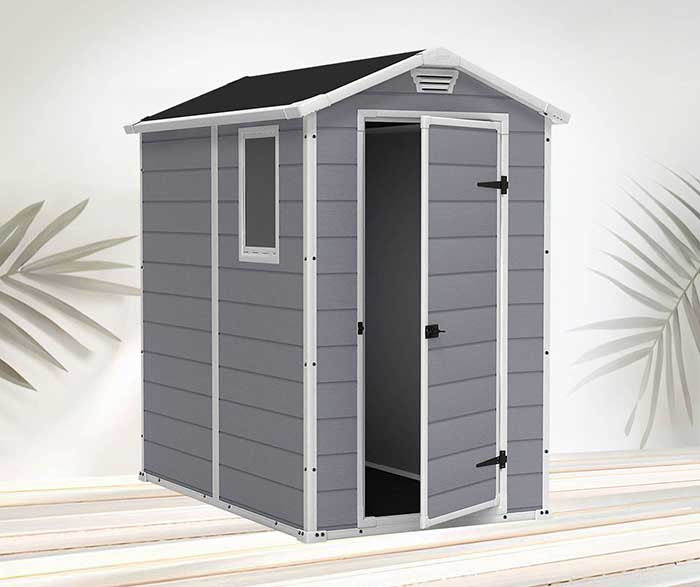 Caseta Keter Manor de plástico de 4x6 gris con puerta entreabierta sobre fondo de terraza maxjardín