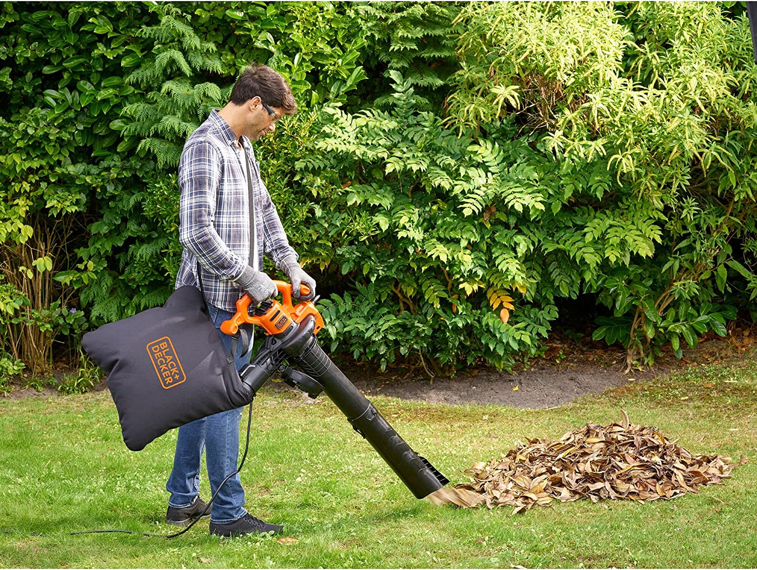 Vista en jardín aspirando con el Aspirador soplador triturador de hojas, 2500W, 310 Km/h. BLACK+DECKER GW2500-QS