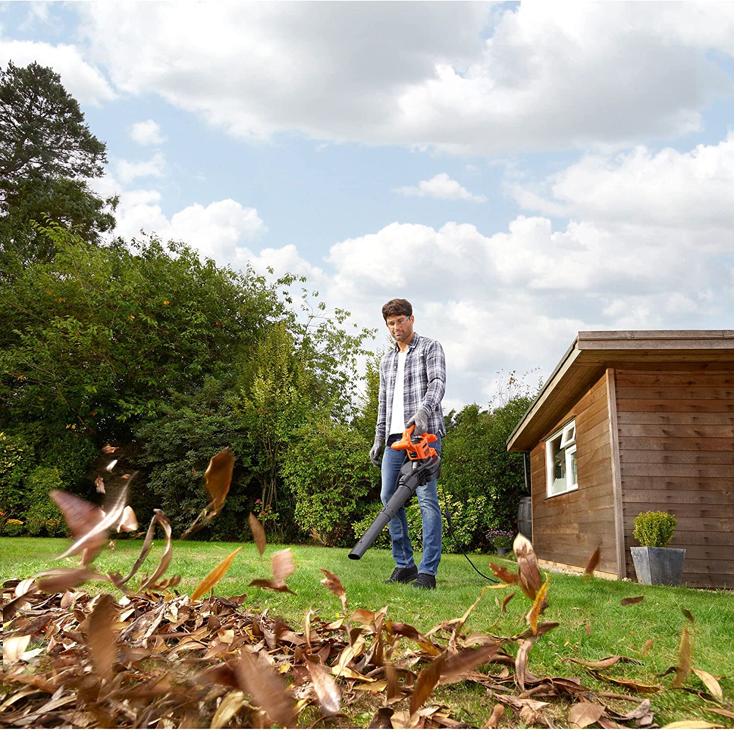 Joven en jardín soplando con el Aspirador soplador triturador de hojas, 2500W, 310 Km/h. BLACK+DECKER GW2500-QS