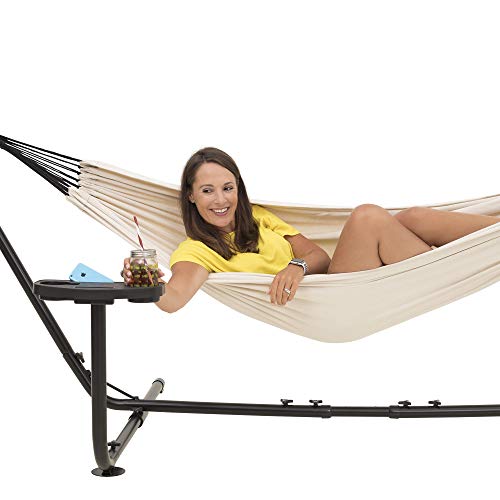 Mujer toma un vaso de su Hamaca con Soporte para 2 Personas con Estante para Colocar Vasos. Soporta hasta 205 kg . 241 x 160 cm. con Funda de Transporte (Beige). VITA5