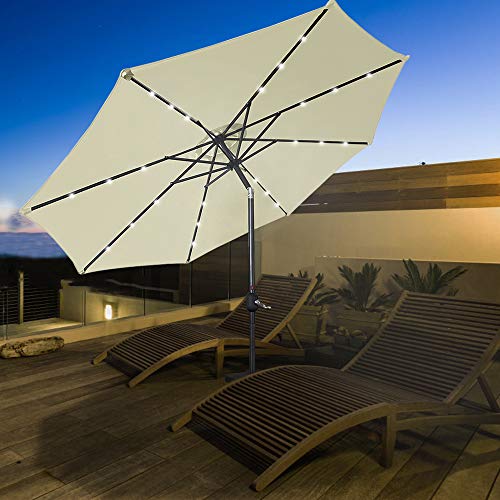 Vista en terraza anocheciendo con Parasol de Aluminio Ø 300 cm con Luces LED solares encendidas, manivela, inclinada en terraza, Beige. HENGMEI