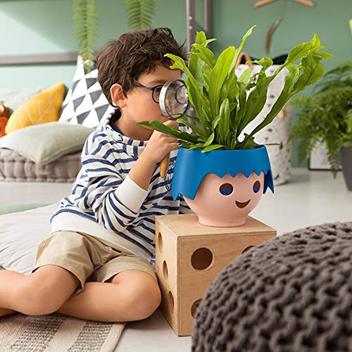 Macetero OJO Ocean Blue con diseño de cabeza de muñeco Playmobil en interior con niño observando planta con una lupa.