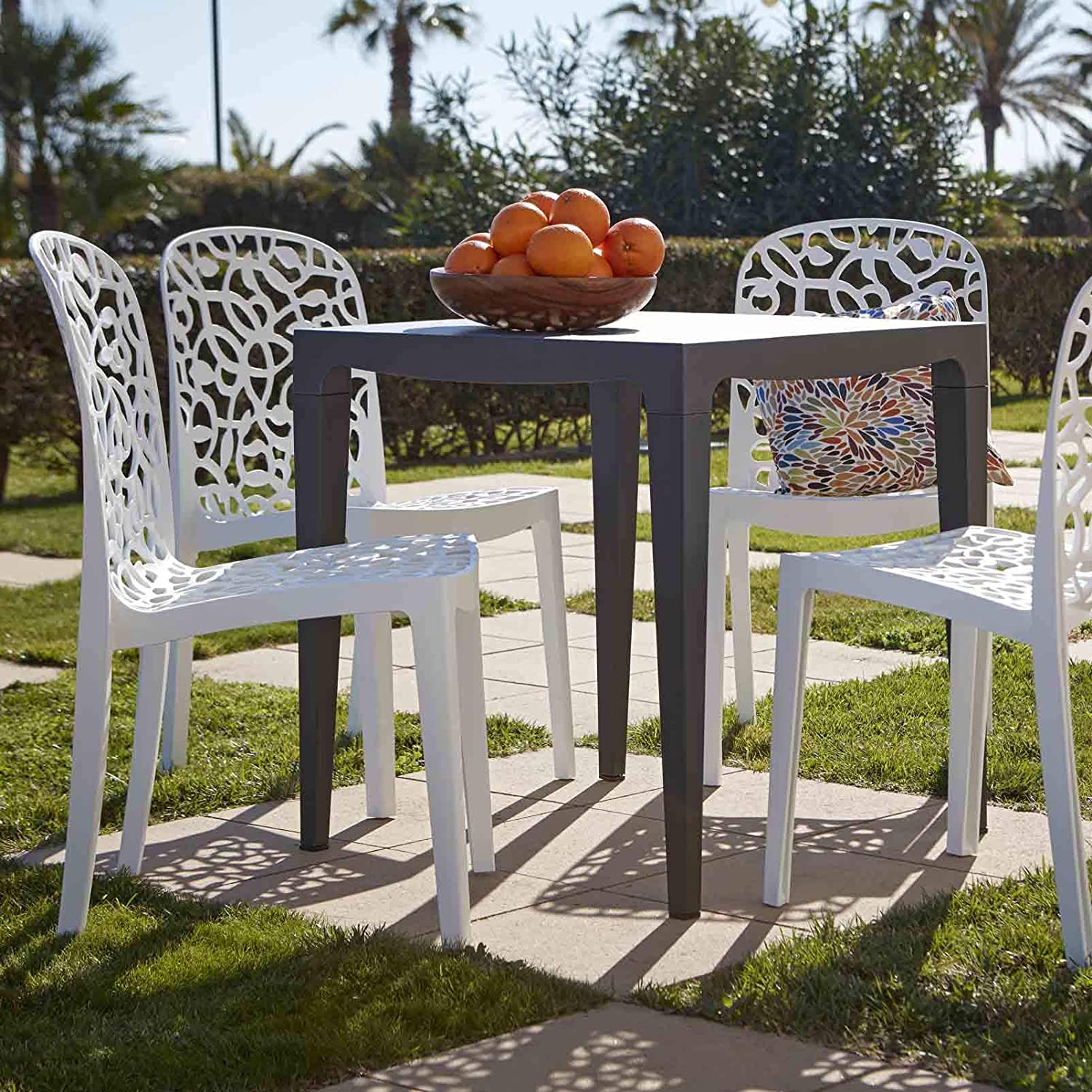 Vista en jardín con mesa y juego de 6 Sillas apilables de interior exterior Flora. 87x50x47 cm, blanco, hecho en España. Shaf