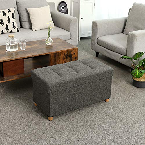Vista en ambiente como reposapiés frente al sofá con el Puff bajo con Almacenaje Plegable Rectangular Tapizado con acolchado de Esponja con Patas de Madera Maciza y Tapa Gris Oscuro LSF16GYZ. SONGMICS