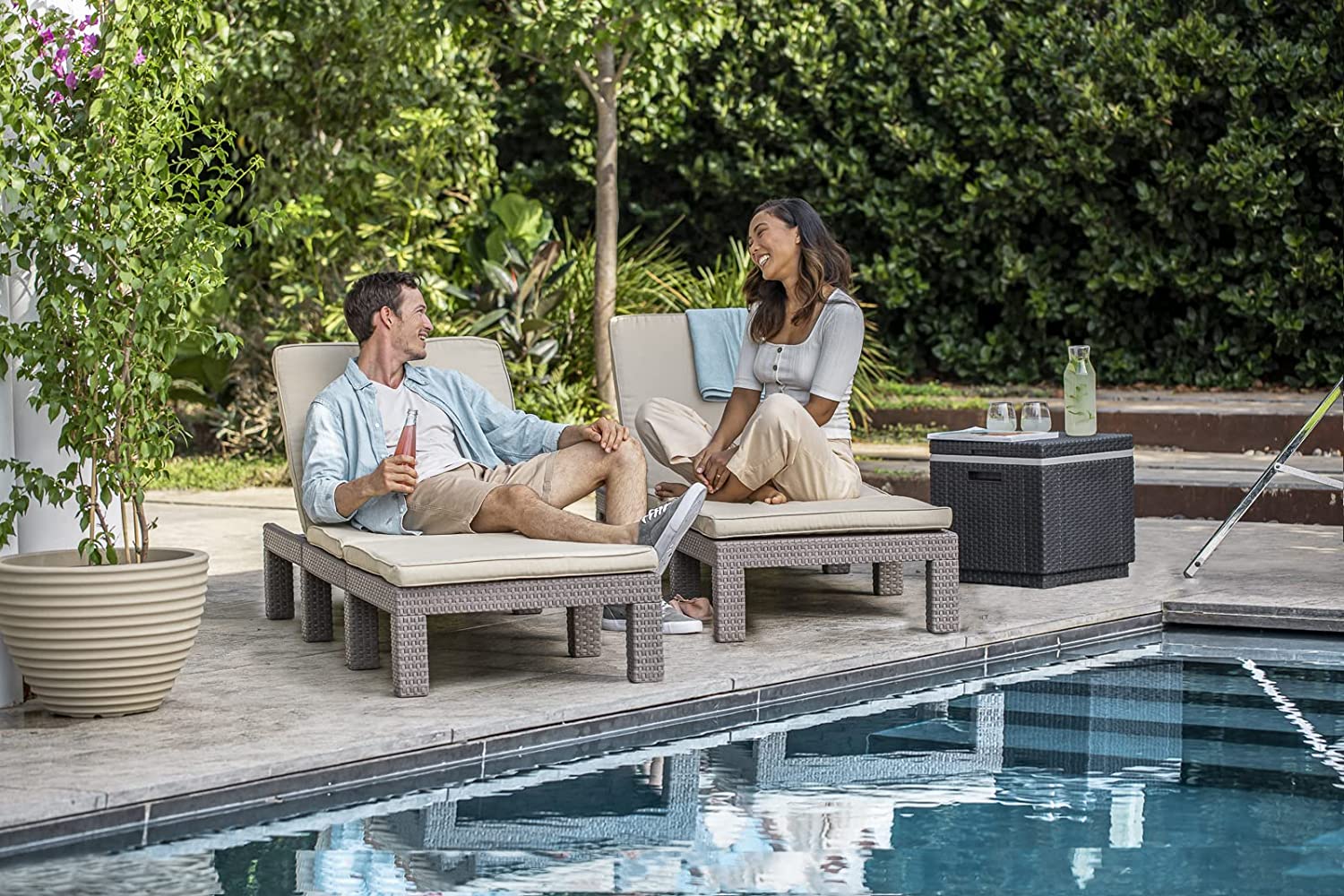 Pareja disfrutando junto a la piscina con sus Tumbonas keter Daytona para jardín color capuchino y cojines beige